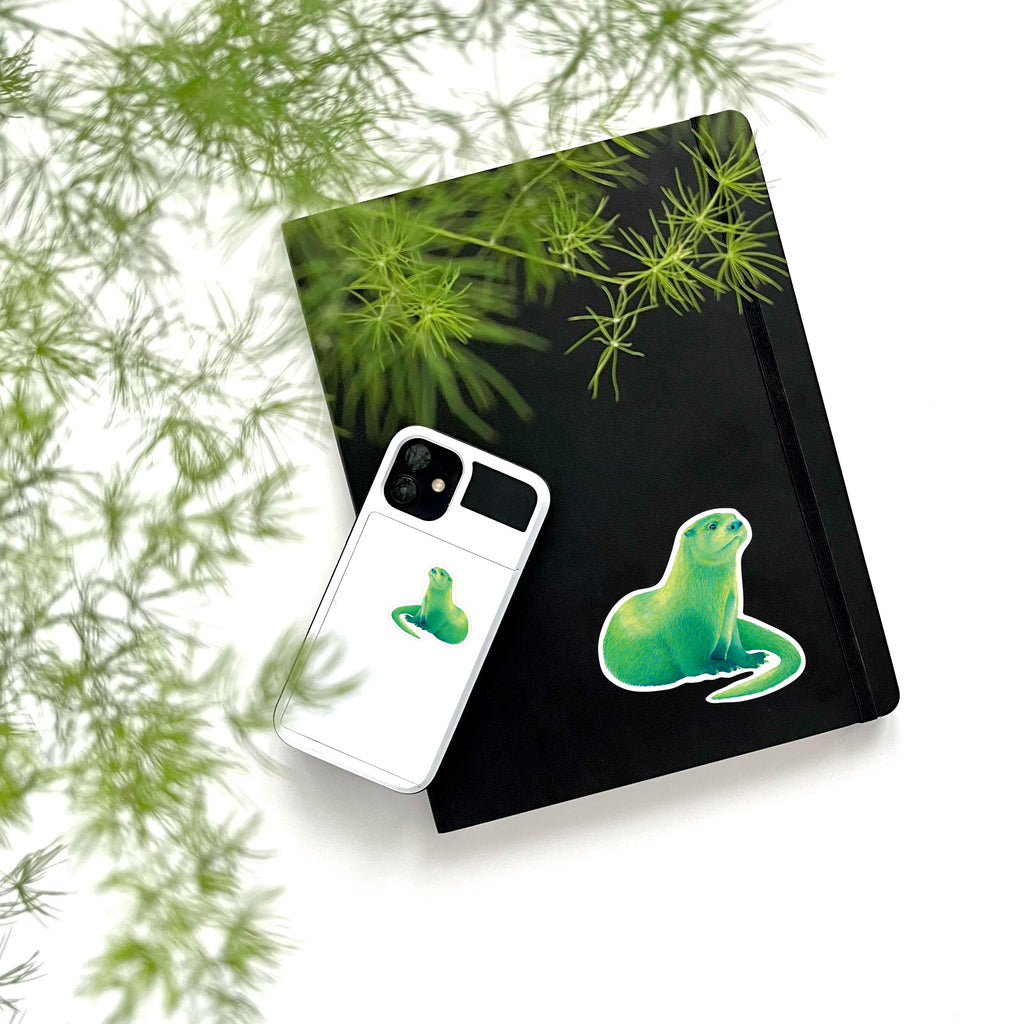 large and small green river otter vinyl stickers on phone and notebook