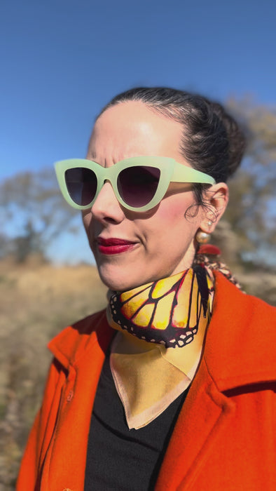 model wearing the large side of the orange monarch butterfly stripe silk scarf