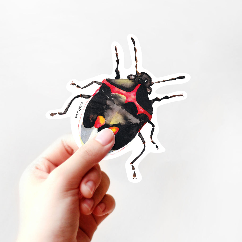 hand holding red and black stink bug vinyl sticker