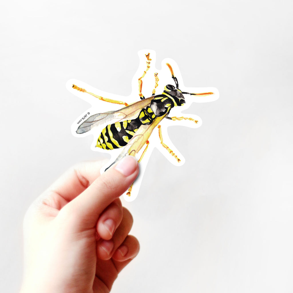 hand holding yellow and black wasp sticker
