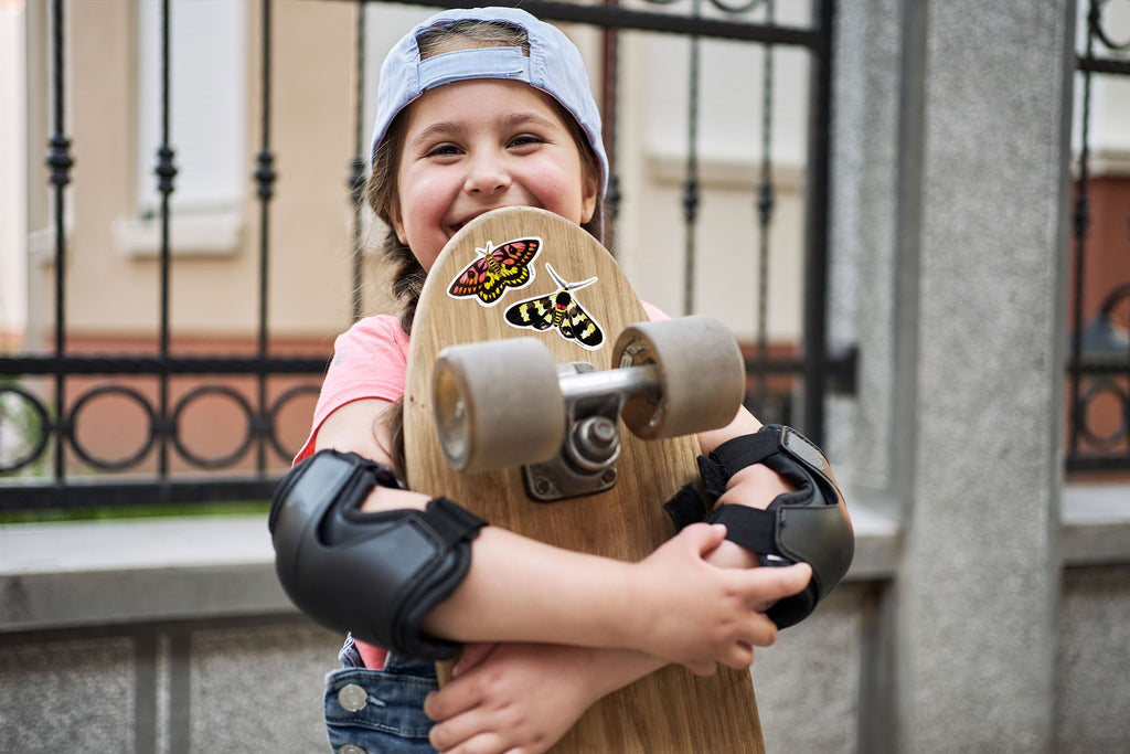 girl holding skateboard decorated with moth stickers